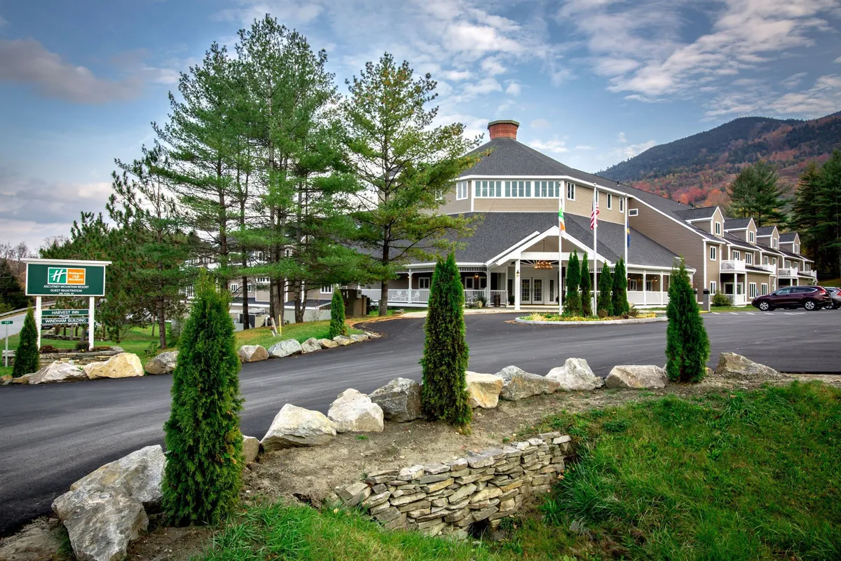 Showcasing the hotel entrance with flag poles and a beautifully landscaped garden, this image highlights the resort’s position amidst mountainous terrain. The inviting walkway suggests easy access to hiking trails and the surrounding natural beauty.